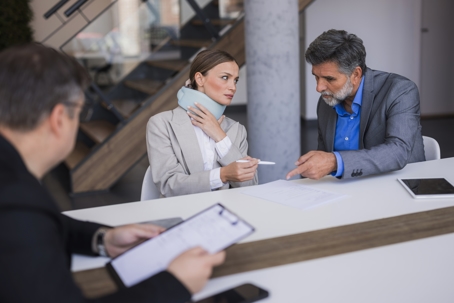 Woman with lawyers and signing documents for insurance claim