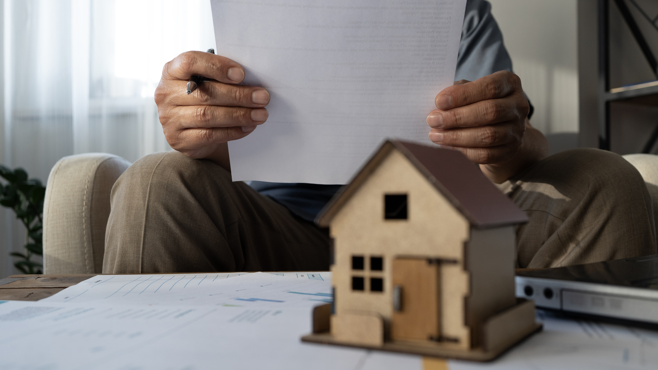 man holding paper and small model house